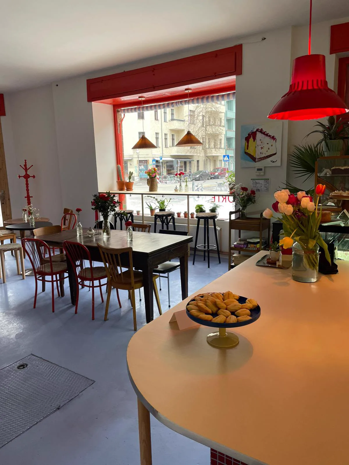 Der Gastraum mit roten Fenstern, Tulpen und Gebäck