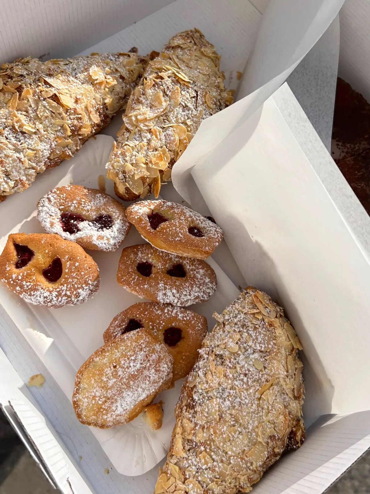 Mandelcroissants und kleine Beerenkuchen in einer Gebäckbox